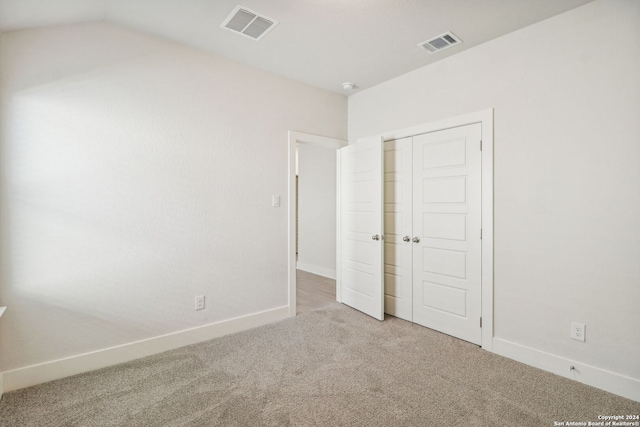 unfurnished bedroom with carpet flooring, lofted ceiling, and a closet