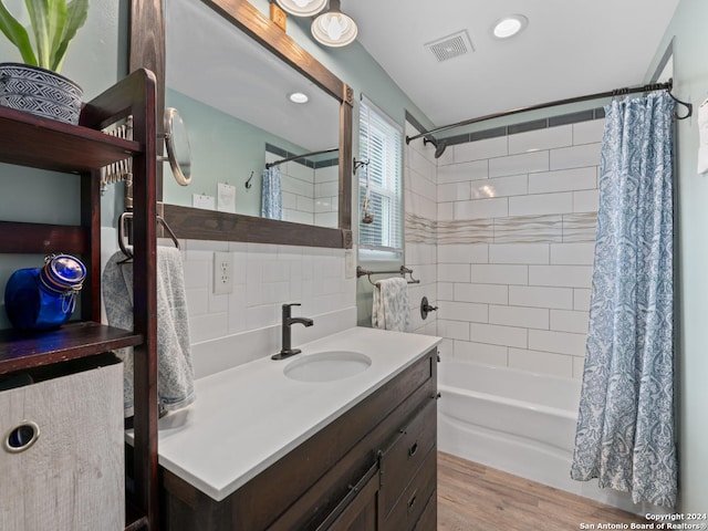 bathroom with hardwood / wood-style flooring, shower / bath combo, vanity, and tile walls