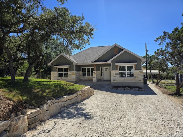 craftsman inspired home featuring stone siding, board and batten siding, and roof with shingles