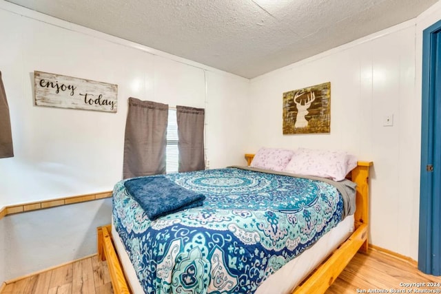 bedroom with a textured ceiling and wood finished floors