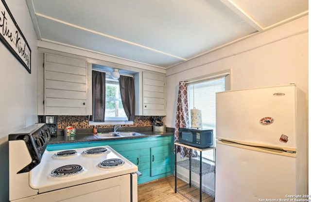 kitchen featuring white appliances, white cabinets, dark countertops, light wood-type flooring, and a sink