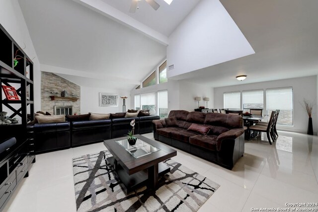 tiled living room featuring ceiling fan, a wealth of natural light, high vaulted ceiling, and a fireplace