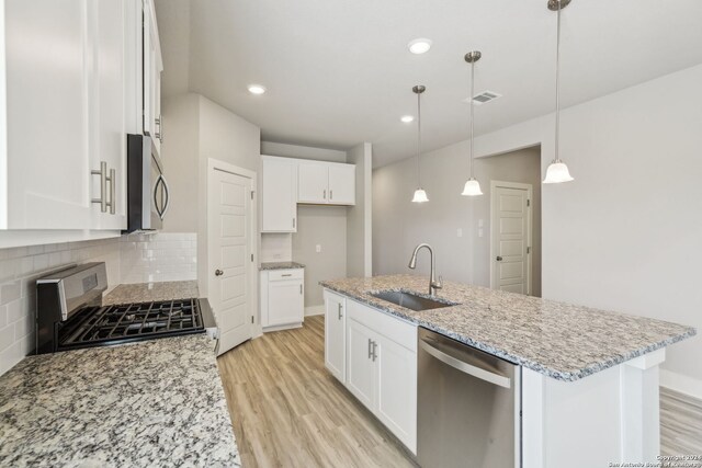 kitchen featuring sink, white cabinetry, stainless steel appliances, and hanging light fixtures