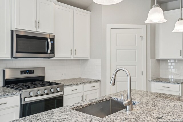 kitchen with tasteful backsplash, pendant lighting, sink, appliances with stainless steel finishes, and white cabinets