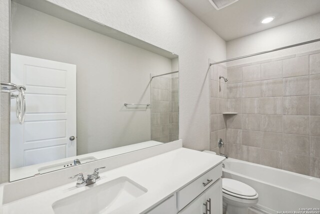 full bathroom featuring toilet, tiled shower / bath, and vanity