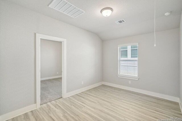 unfurnished room with lofted ceiling and light hardwood / wood-style floors