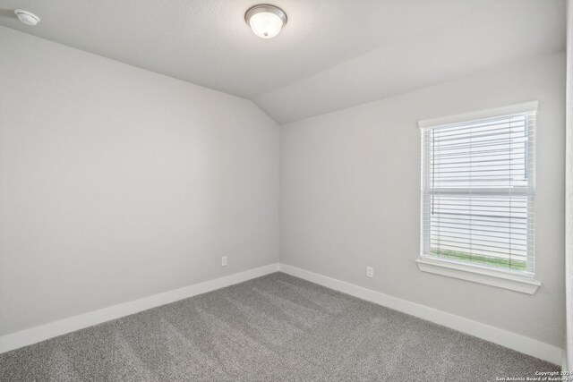 carpeted empty room featuring lofted ceiling