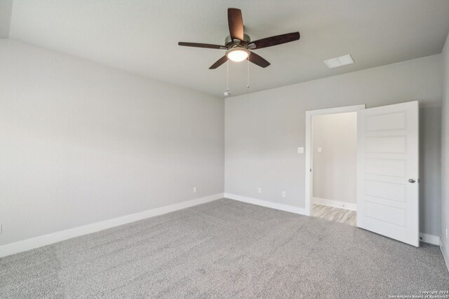 spare room with ceiling fan and light colored carpet