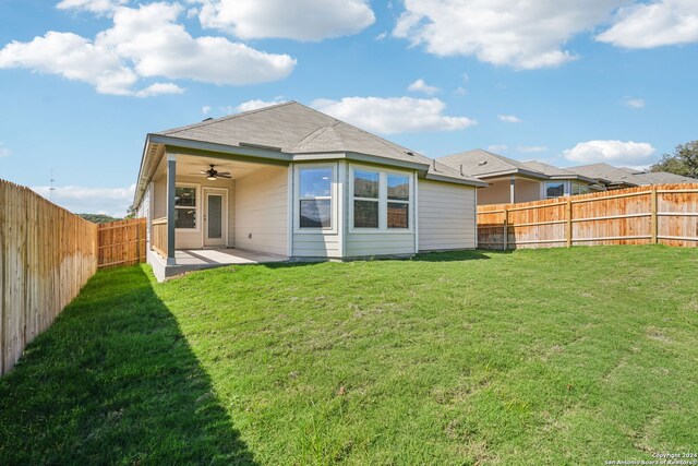 rear view of house featuring ceiling fan, a yard, and a patio