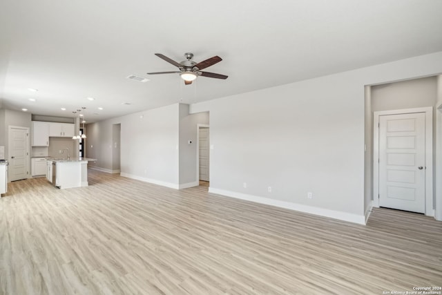 unfurnished living room featuring ceiling fan, light wood-type flooring, and sink