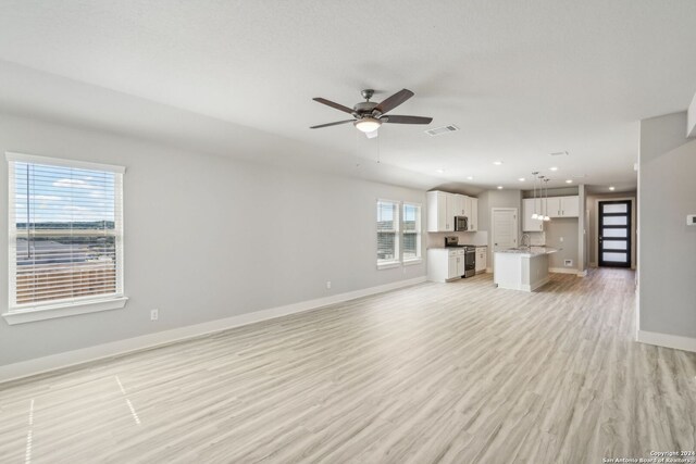 unfurnished living room featuring ceiling fan, sink, and light wood-type flooring