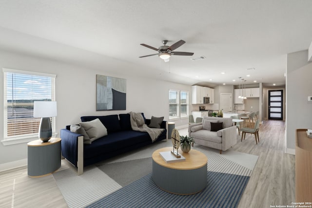 living room with ceiling fan, sink, and light hardwood / wood-style flooring