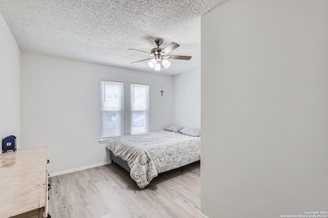 bedroom with a textured ceiling, light hardwood / wood-style flooring, and ceiling fan