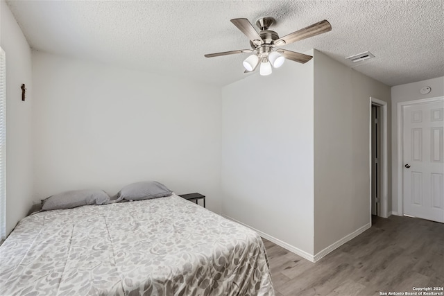 bedroom with ceiling fan, light hardwood / wood-style flooring, and a textured ceiling