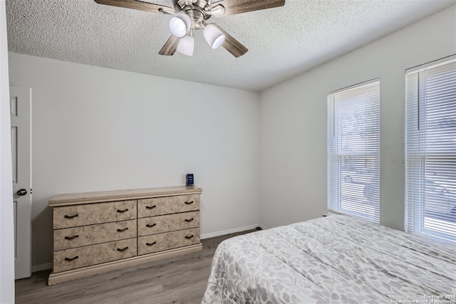 bedroom featuring ceiling fan, light hardwood / wood-style floors, and a textured ceiling