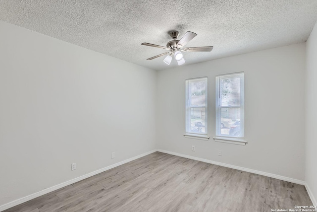 spare room with ceiling fan, light wood-type flooring, and a textured ceiling