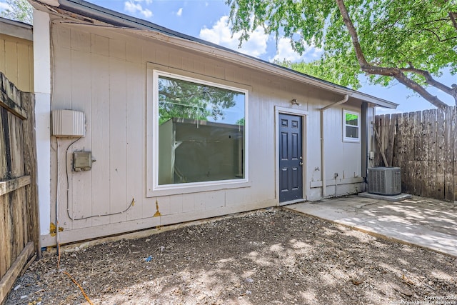 view of exterior entry with central AC unit and a patio area