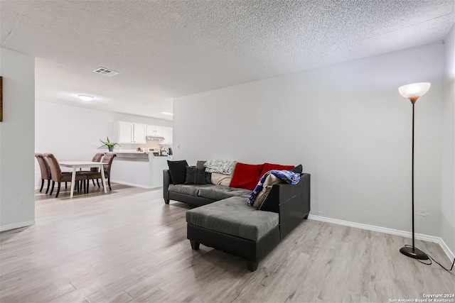 living room with light wood-type flooring and a textured ceiling