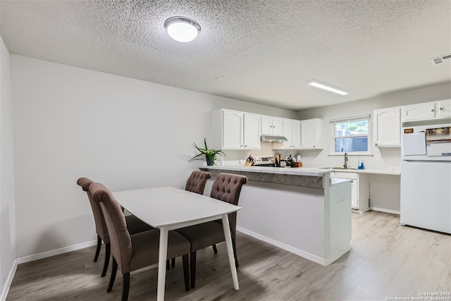 kitchen featuring kitchen peninsula, a textured ceiling, sink, white cabinets, and white fridge