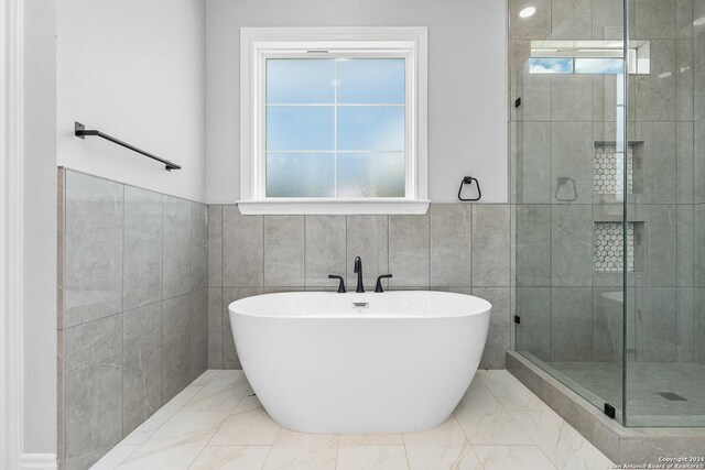 bathroom featuring plus walk in shower, tile walls, and tile patterned flooring