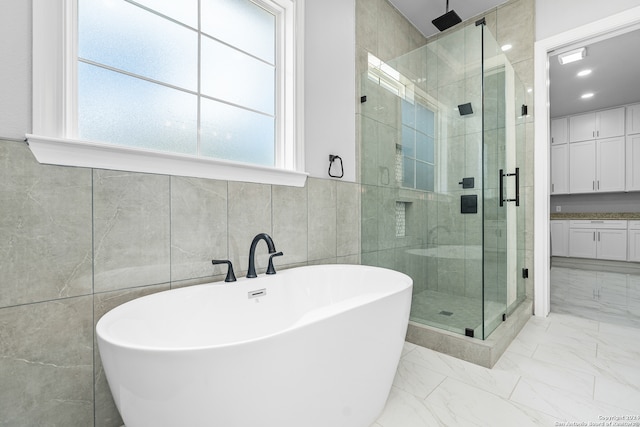 bathroom with shower with separate bathtub, tile walls, and tile patterned floors