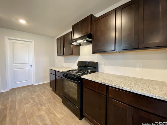 kitchen with dark brown cabinetry, light hardwood / wood-style floors, light stone counters, and black range with gas cooktop