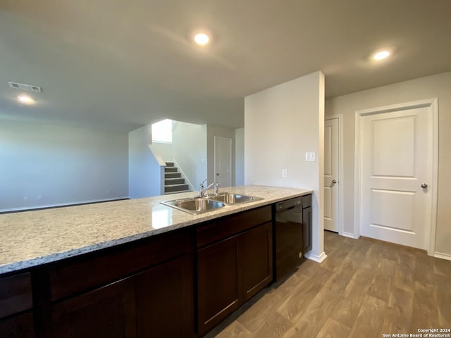 kitchen with light wood-type flooring, light stone counters, dark brown cabinetry, sink, and dishwasher