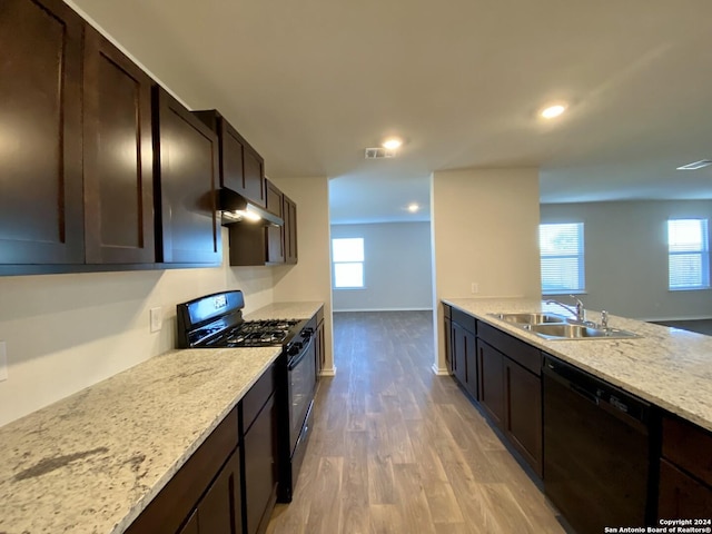 kitchen with black appliances, sink, dark brown cabinets, light hardwood / wood-style floors, and light stone counters