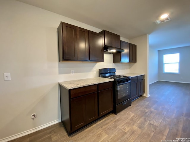 kitchen featuring light wood-type flooring, range hood, gas stove, light stone counters, and dark brown cabinetry