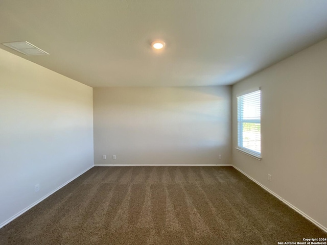 spare room with dark colored carpet