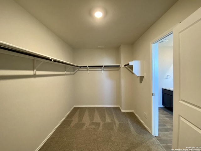 walk in closet featuring dark carpet