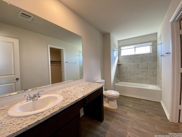 full bathroom featuring tiled shower / bath, hardwood / wood-style floors, vanity, and toilet