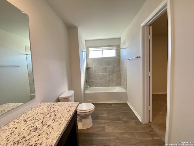 full bathroom featuring tiled shower / bath, vanity, wood-type flooring, and toilet