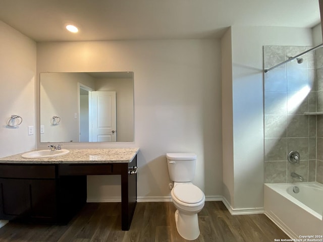 full bathroom featuring vanity, hardwood / wood-style floors, tiled shower / bath combo, and toilet