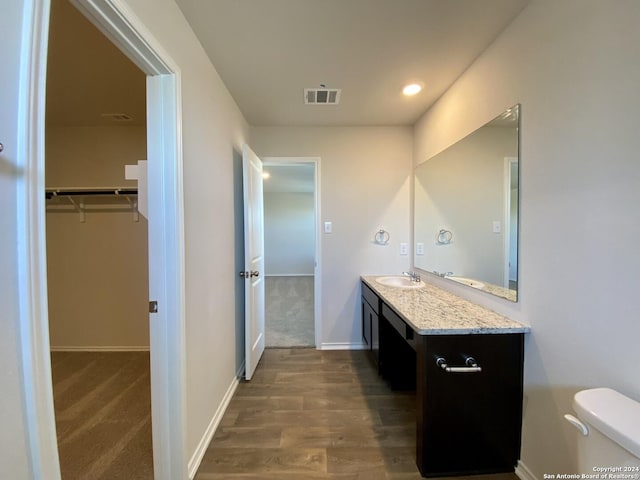 bathroom featuring wood-type flooring, vanity, and toilet