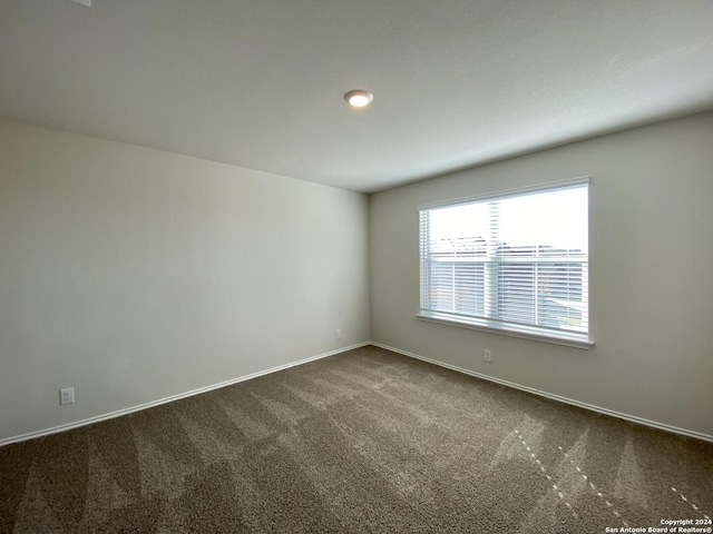 unfurnished room with dark colored carpet