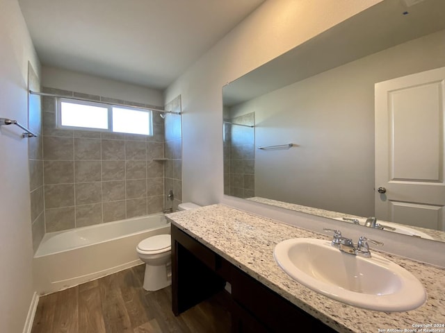 full bathroom featuring vanity, tiled shower / bath combo, hardwood / wood-style flooring, and toilet