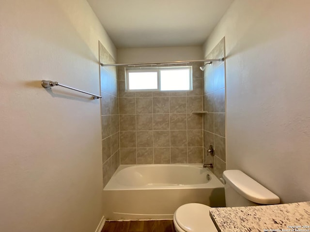 bathroom featuring toilet, wood-type flooring, and tiled shower / bath