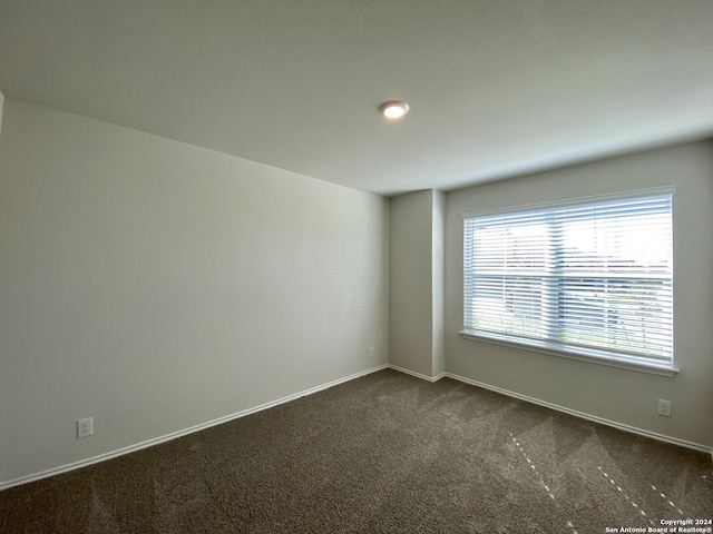 unfurnished room featuring dark colored carpet