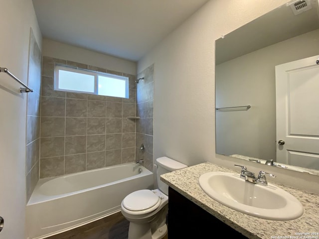 full bathroom featuring vanity, wood-type flooring, tiled shower / bath combo, and toilet