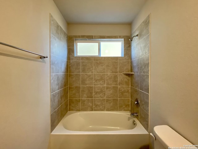 bathroom featuring tiled shower / bath combo and toilet