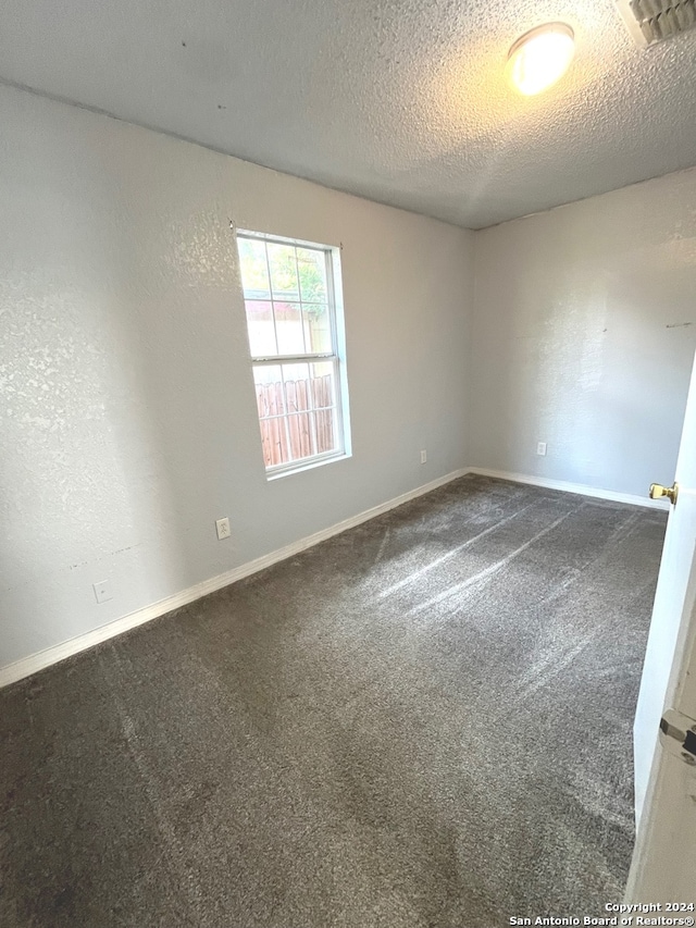 carpeted spare room with a textured ceiling