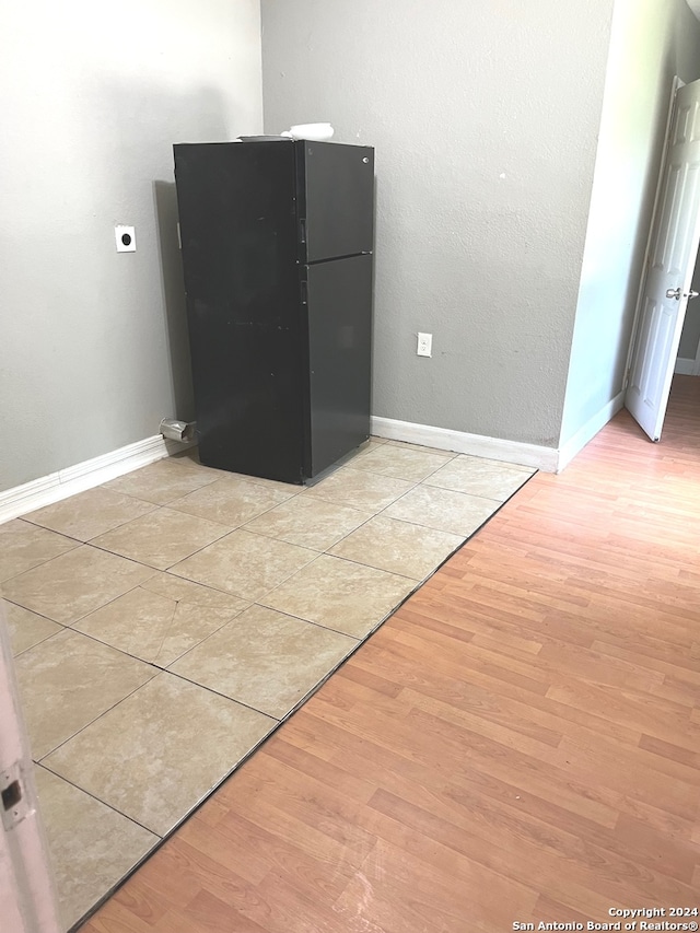 room details with black fridge and hardwood / wood-style floors