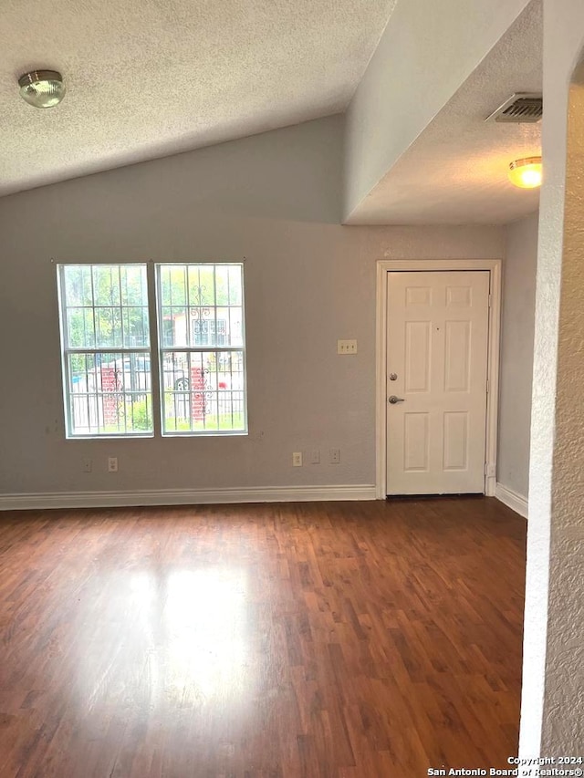 unfurnished room with a textured ceiling, wood-type flooring, and lofted ceiling