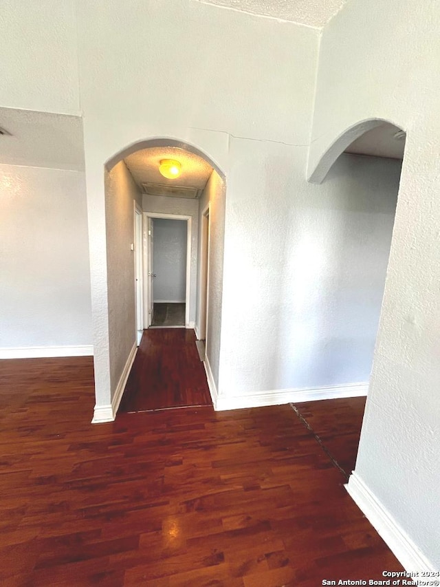 corridor featuring a textured ceiling and wood-type flooring