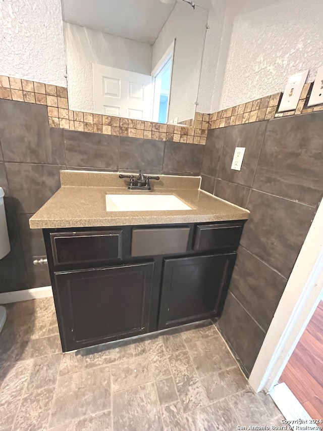 bathroom featuring vanity, backsplash, hardwood / wood-style flooring, and tile walls