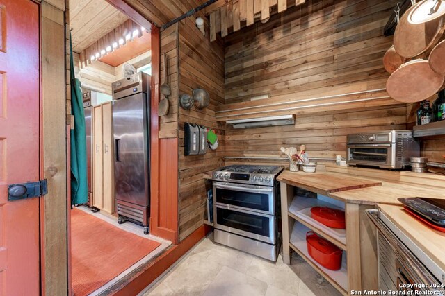 kitchen featuring wood ceiling, wood walls, and stainless steel built in fridge