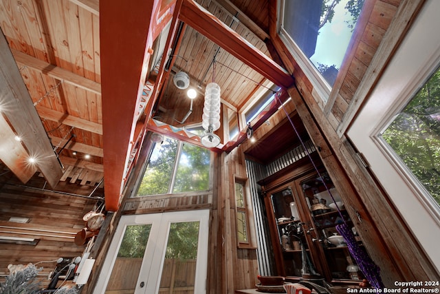 interior space with wood ceiling, beamed ceiling, and wooden walls