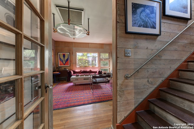 staircase featuring wood-type flooring, wood walls, and a healthy amount of sunlight