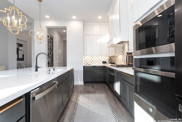 kitchen featuring sink, an inviting chandelier, pendant lighting, white cabinets, and appliances with stainless steel finishes